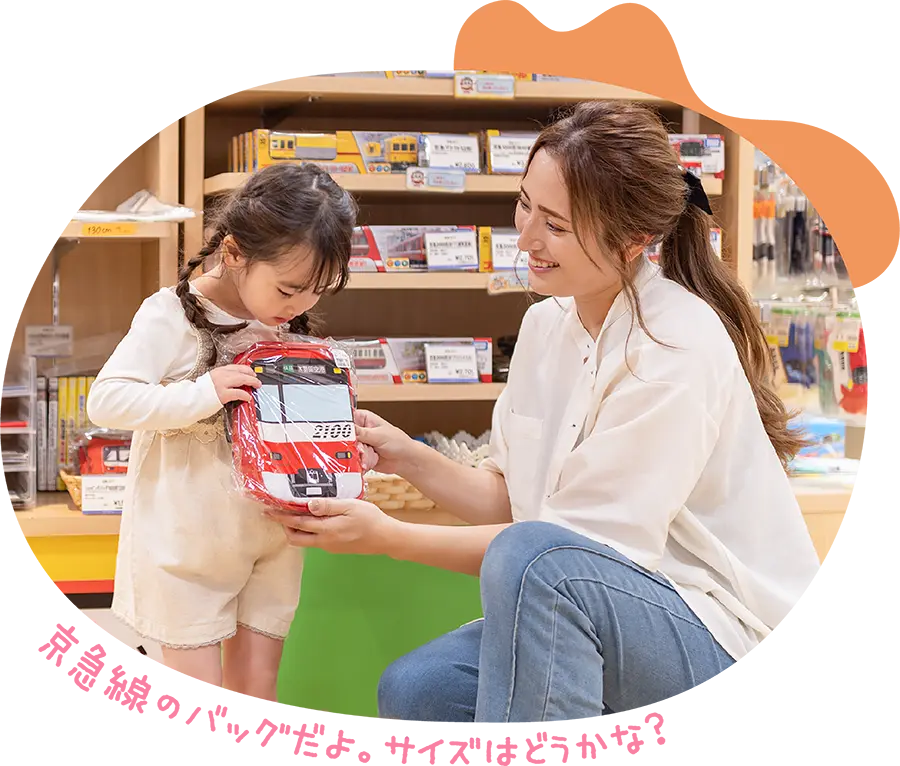 京急線のバッグだよ。サイズはどうかな？と女の子にバッグを手渡すお母さん